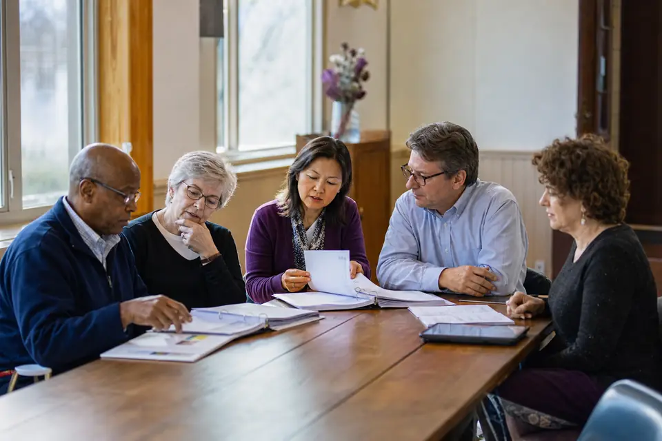 Nonprofit board members reviewing binders together around a meeting table